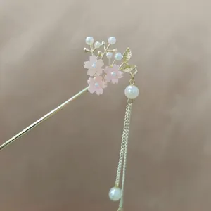 Detail of a golden tassel hair pin with pink cherry blossoms and white pearls