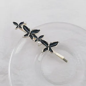 Eleganter goldfarbener Haarclip mit drei schwarzen Emaille-Schmetterlingen und Perlen