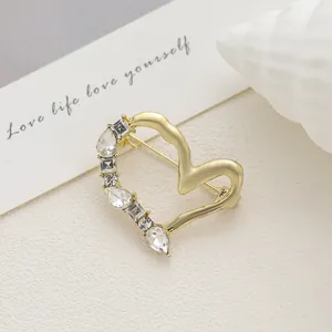 Détail d'une broche cœur dorée avec cristaux sur un fond beige texturé élégant