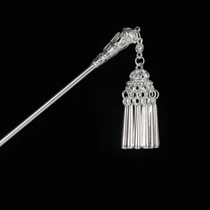 Macro shot of silver retro hair stick featuring intricate hollow carving and tassel charms