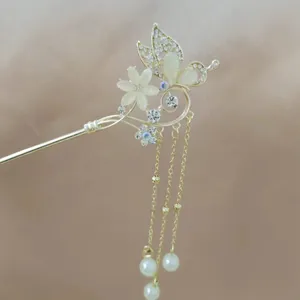 Detailed view of golden butterfly hair pin with tassels and white resin flower