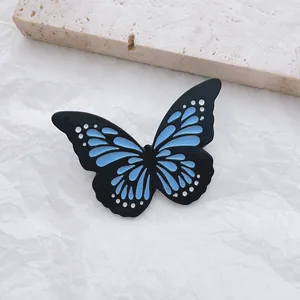 Detailed close-up of a luminous butterfly enamel pin with blue and black wing textures