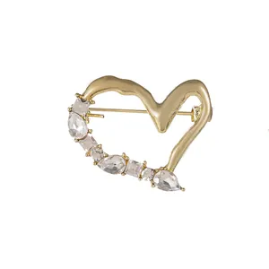Broche cœur dorée avec cristaux de diverses formes sur un fond blanc pour vêtements