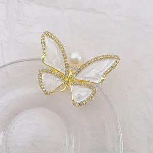 Detail of elegant butterfly brooch with gold plating, white enamel, and a large central pearl