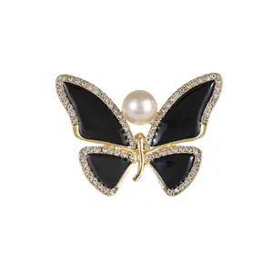 Elegant butterfly brooch with black enamel, sparkling rhinestones, and a large central pearl