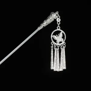 Macro shot of silver hair stick with hollow butterfly pendant and textured tassels