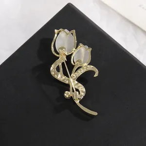 Elegant gold tulip brooch with cat eye stones and rhinestones shown on a black display stand