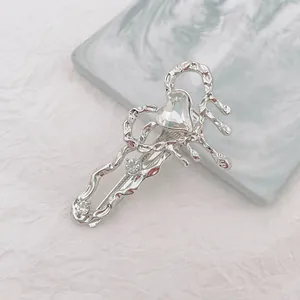 Detalle de la pinza para el pelo de corazón en metal líquido plateado con cristal