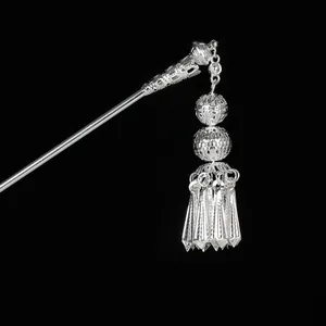 Detailed macro shot of vintage silver hair stick with hollow spheres and dangling tassels