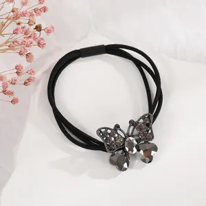 Detailansicht eines schwarzen Haargummis mit einem strassbesetzten Schmetterling-Charm