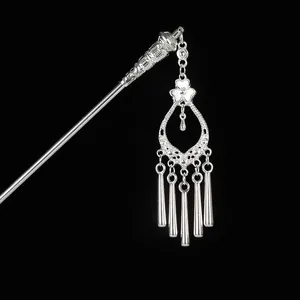 Close-up of vintage silver hair pin with hollow flower and long metallic tassels