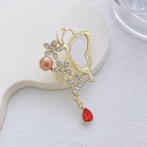 Detailansicht goldene Schmetterling Brosche mit rosa Perle und rotem Edelstein Anhänger