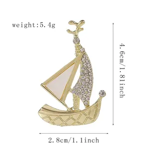 Detailed view of sailboat brooch with gold alloy, white enamel and sparkling rhinestones
