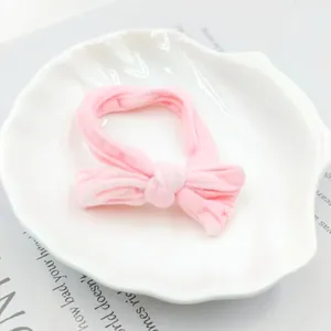 Detail of pink bow hair band on a white shell tray with high elasticity and soft fabric