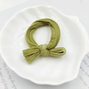 Close-up of olive green velvet scrunchie with bow detail in a white shell dish