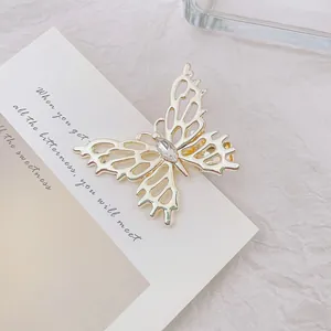 Primer plano de pinza de pelo mariposa dorada con alas caladas y cristal brillante