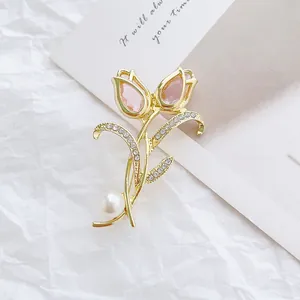 Détail de broche tulipe avec cristaux roses, zircons blancs et perle sur métal doré