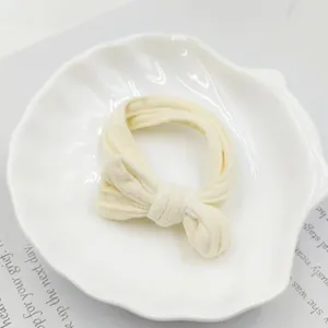 Close-up of a seamless creamy white bow hair tie on an elegant shell-shaped ceramic plate