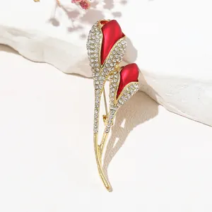 Détail de la broche tulipe en satin rouge avec strass sur un fond de roche blanche