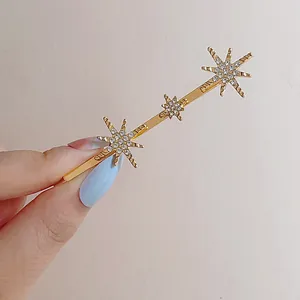 Eleganter goldener Haarclip mit drei Strass-Sternen auf minimalistischer Metallbasis