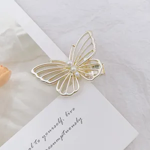 Detalle de una pinza para el pelo de mariposa dorada calada con perlas sobre tarjeta