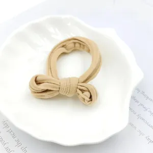 Detailed close-up of a soft khaki fabric hair scrunchie with bow knot on shell tray
