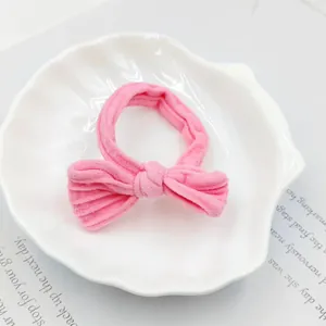 Close-up of pink ribbed fabric bow hair tie on a white shell decorative plate