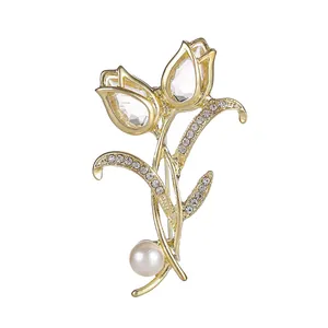 Broche tulpe dorée élégante avec pétales en cristal et perle blanche sur fond blanc pur