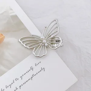 Primer plano de la pinza de mariposa plateada calada con tres elegantes perlas blancas