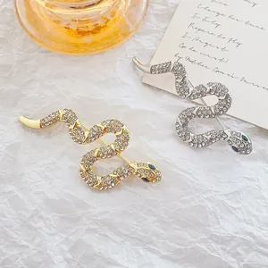 Exquisite snake brooch with white rhinestones and blue eyes in gold and silver finish