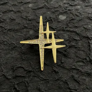 Broche étoile dorée multicouche avec strass brillants sur fond noir texturé élégant