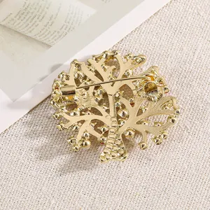 Élégante broche en forme d'arbre doré avec strass sur un fond de tissu texturé chic