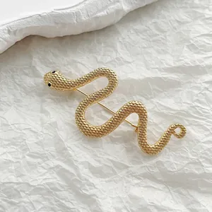 Macro detail of golden snake brooch featuring textured scales and black stone eyes