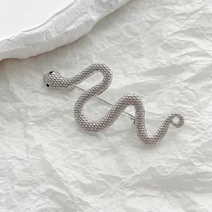 Detailed macro view of silver snake brooch with scale texture and black bead eyes