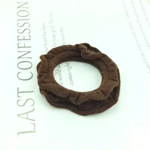 Close-up of a dark brown ruffle edge scrunchie made of elastic fabric on white paper