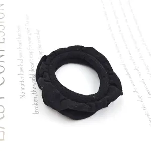 Detailed view of black ruffled fabric hair scrunchie with soft pleated texture and high elasticity