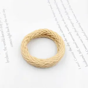 Detailed view of the woven beige ruffled hair tie featuring a soft textured braided design