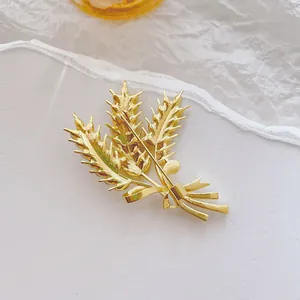 Elegante spilla a spiga di grano dorata con strass e fiocco su sfondo bianco