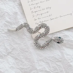 Silver snake brooch with sparkling rhinestones and blue gemstone eyes on textured background