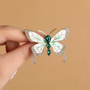 Eleganter Schmetterling-Brosche mit weißem Emaille und grünen Edelsteinen in Gold
