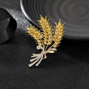 Dettaglio spilla a spiga di grano con cristalli dorati e fiocco di strass su seta