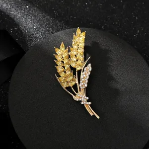 Dettaglio macro di spilla spiga di grano dorata con cristalli gialli e zirconi lucenti