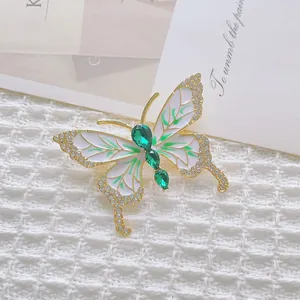 Eleganter Schmetterling Brosche mit weißer Emaille, grünen Steinen und Goldakzenten auf Strick
