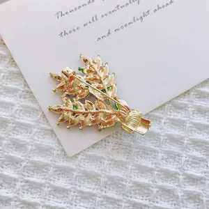 Élégante broche feuille verte avec dorure sur une carte blanche et fond texturé