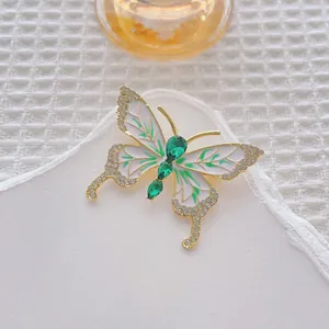 Makroaufnahme der Schmetterlingsbrosche mit goldenen Flügeln und grünen Edelsteinen