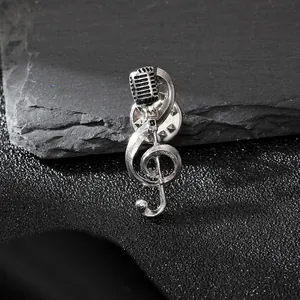 Dettaglio della spilla a forma di nota musicale e microfono in argento vintage con clip