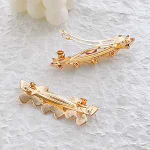 Barrettes à cheveux dorées élégantes aux motifs de fleurs et d'étoiles sur fond blanc texturé