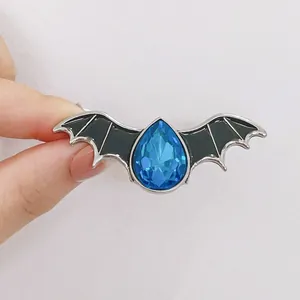 Halloween bat wing brooch with pear-shaped blue crystal and black enamel wings