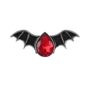Gothic bat brooch with black enamel wings and a faceted red teardrop crystal accent