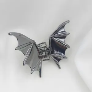 Détail macro d'une pince à cheveux en métal gris foncé en forme d'aile de chauve-souris